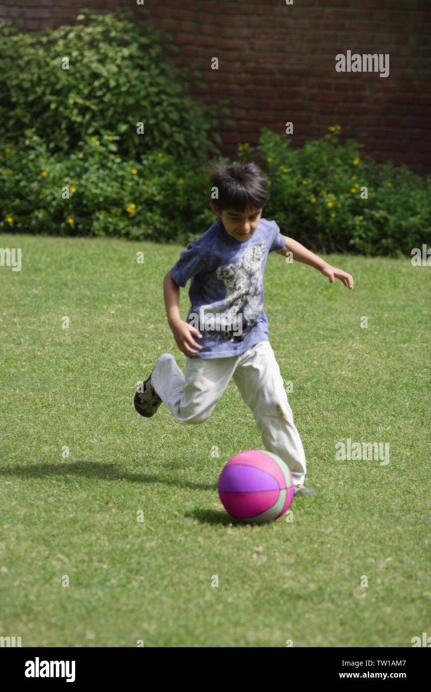 Junge spielt Fußball in einem Feld Stockfoto