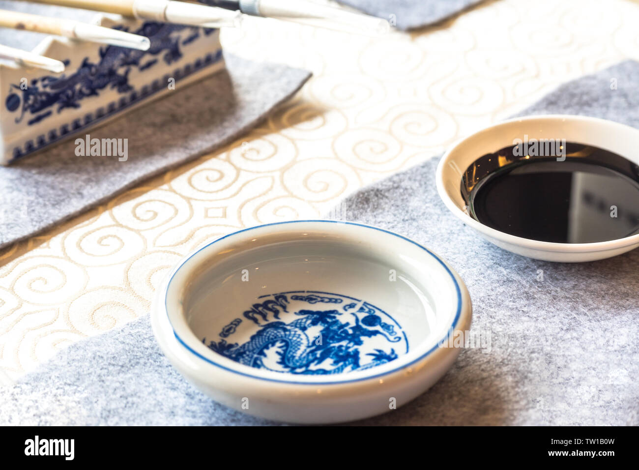 Keramikschale mit schwarzer Tinte auf Tisch Stockfoto