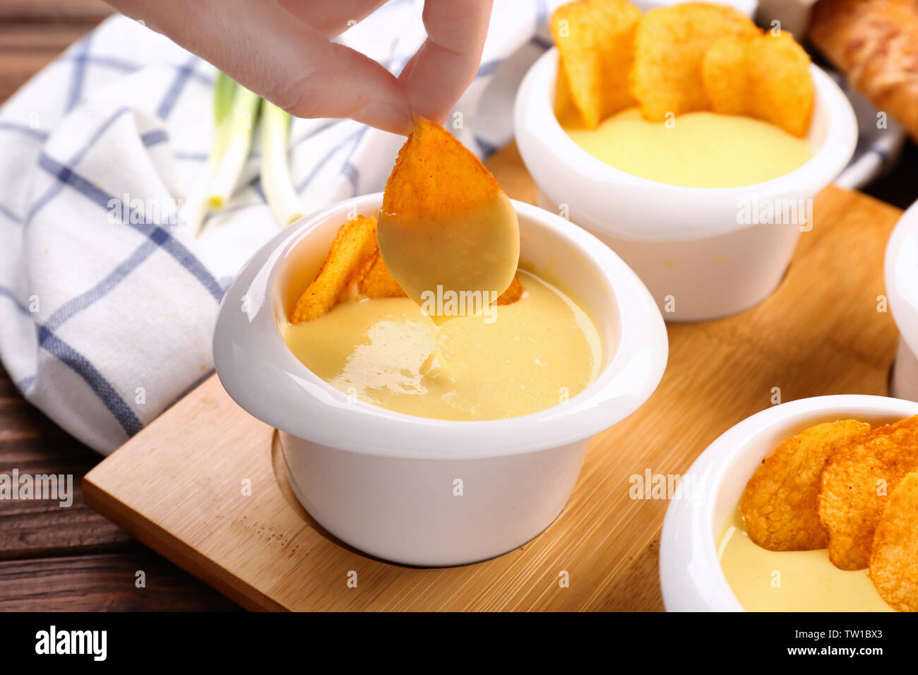 Weibliche Hand tauchen Chip in der Schüssel mit Bier Käse dip, Nahaufnahme Stockfoto