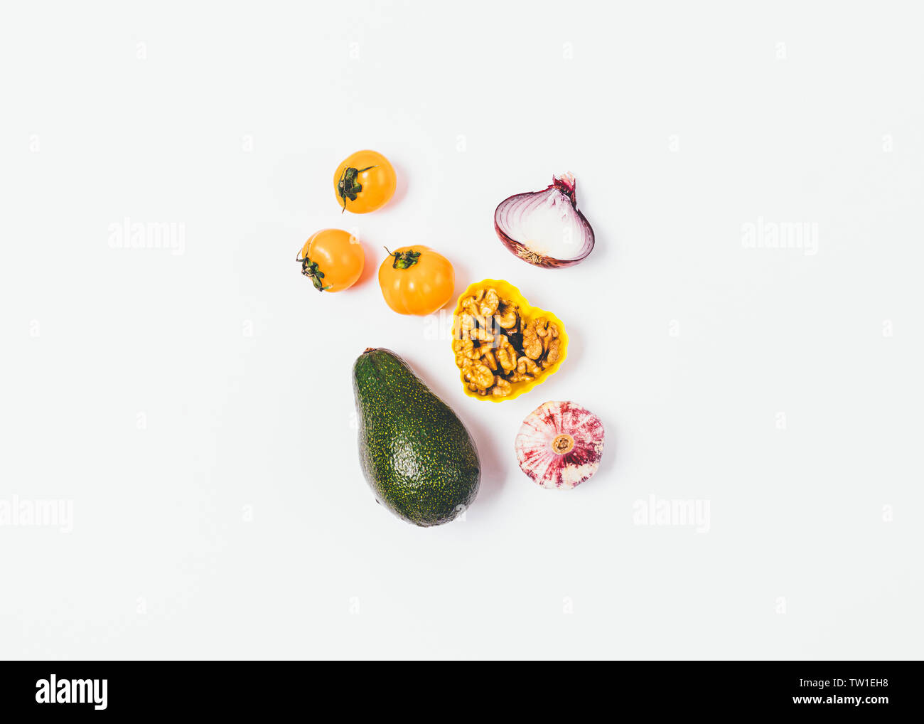 Minimale flach Anordnung von gesunden Verhältnis von reife Avocados, Nüsse, Zwiebeln, Knoblauch und gelbe Kirschtomaten auf weißem Hintergrund. Stockfoto