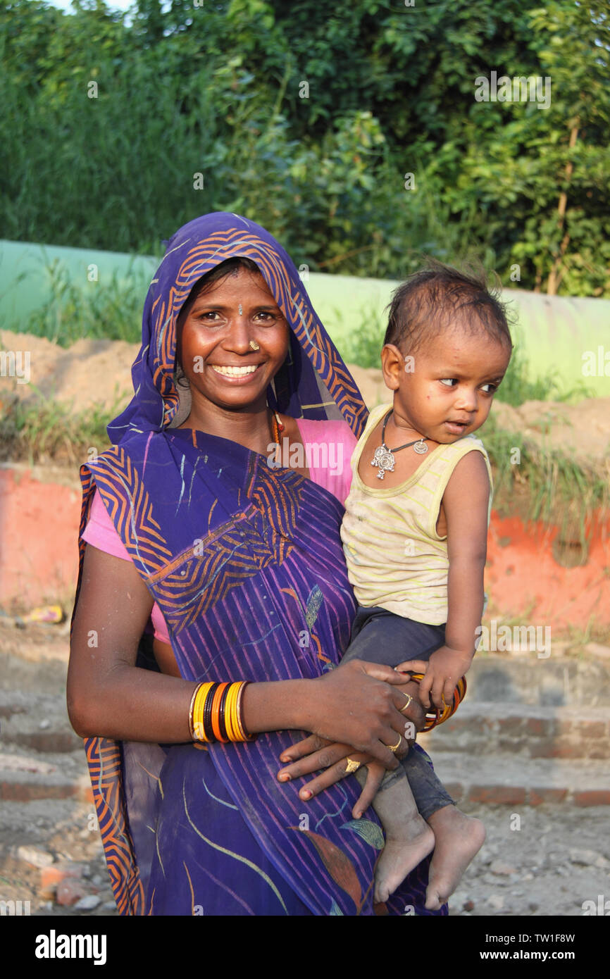 Frau, die ihr Baby trägt und lächelt, Indien Stockfoto