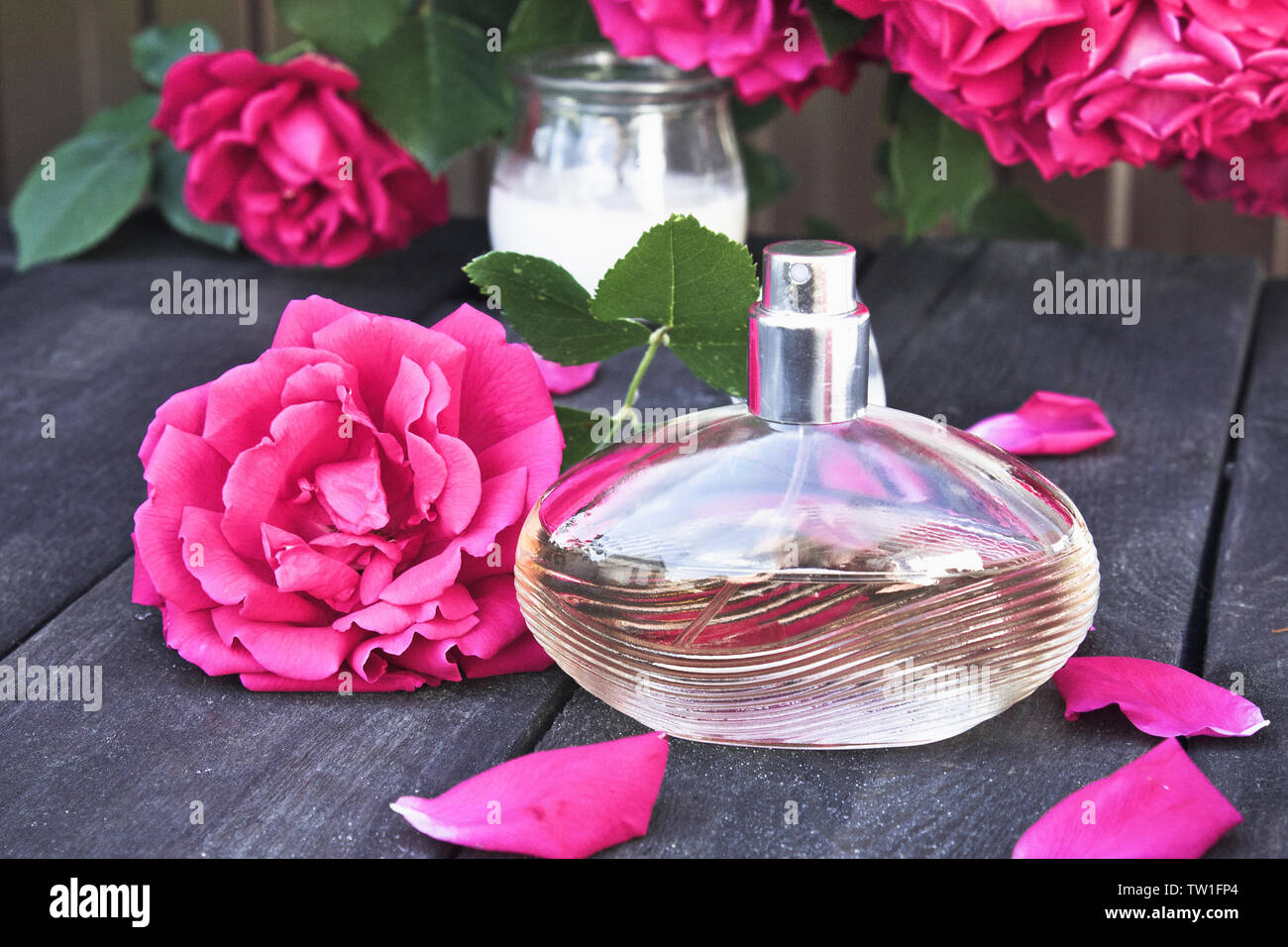 Flasche Frauen Düfte mit roten Rosen auf dem Hintergrund der dunklen Holz. Aromatherapie Stockfoto