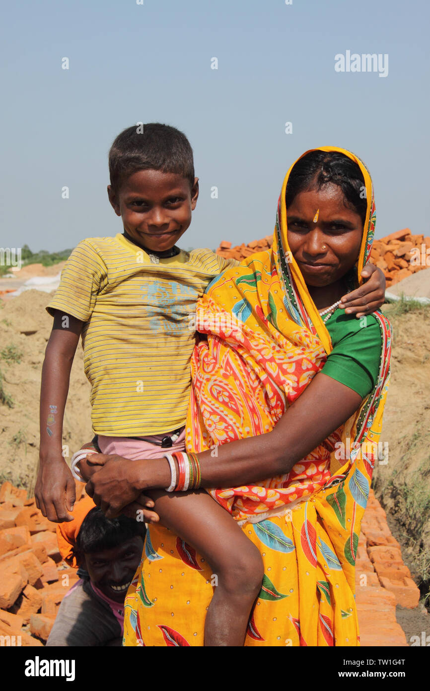 Frau, die ihren Sohn auf einer Baustelle in Indien trägt Stockfoto