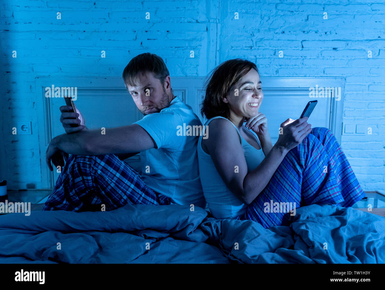 Lifestyle Portrait von Happy Freundin Frau Handy im Bett und wütend, traurig, frustriert Mann Freund am Telefon Langeweile süchtig ignorieren Stockfoto