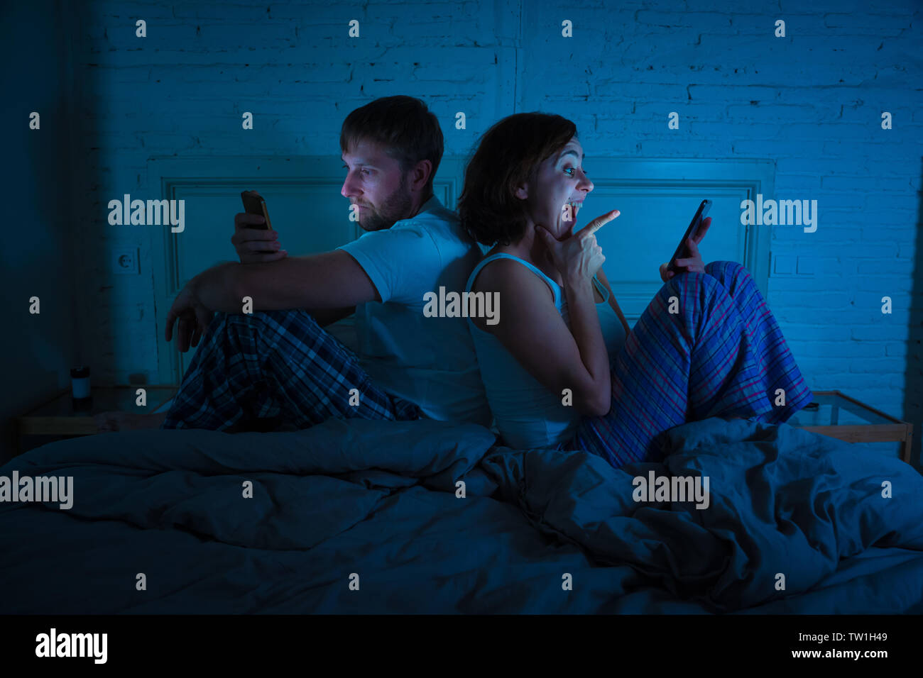 Lifestyle Portrait von Happy Freundin Frau Handy im Bett und wütend, traurig, frustriert Mann Freund am Telefon Langeweile süchtig ignorieren Stockfoto