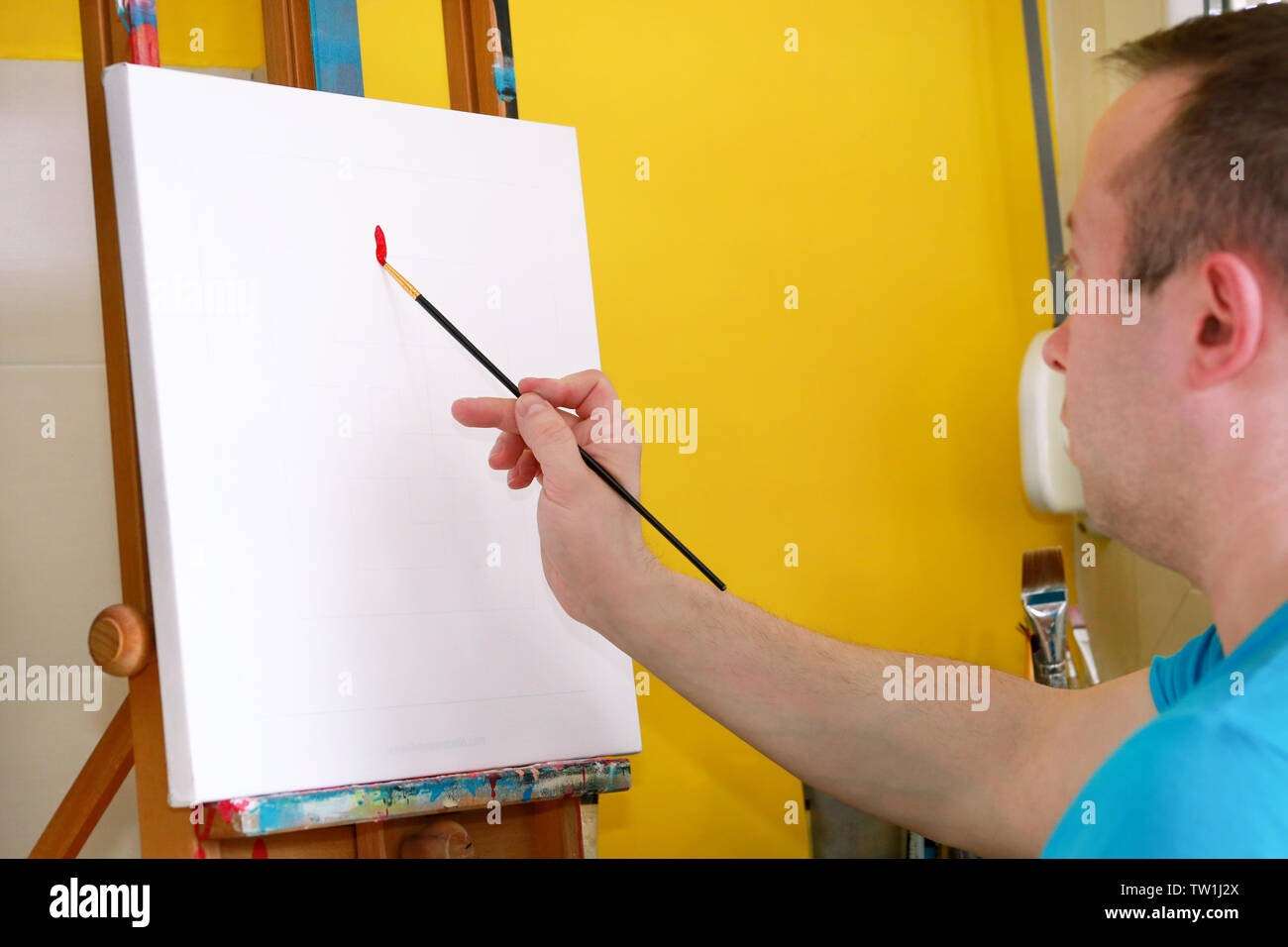 Männliche Künstler Maler arbeiten in Workshops mit Leinwand auf Holz Reißbrett Staffelei in der Kunst malen Studio. Porträt des Künstlers mit Pinsel malt. Stockfoto