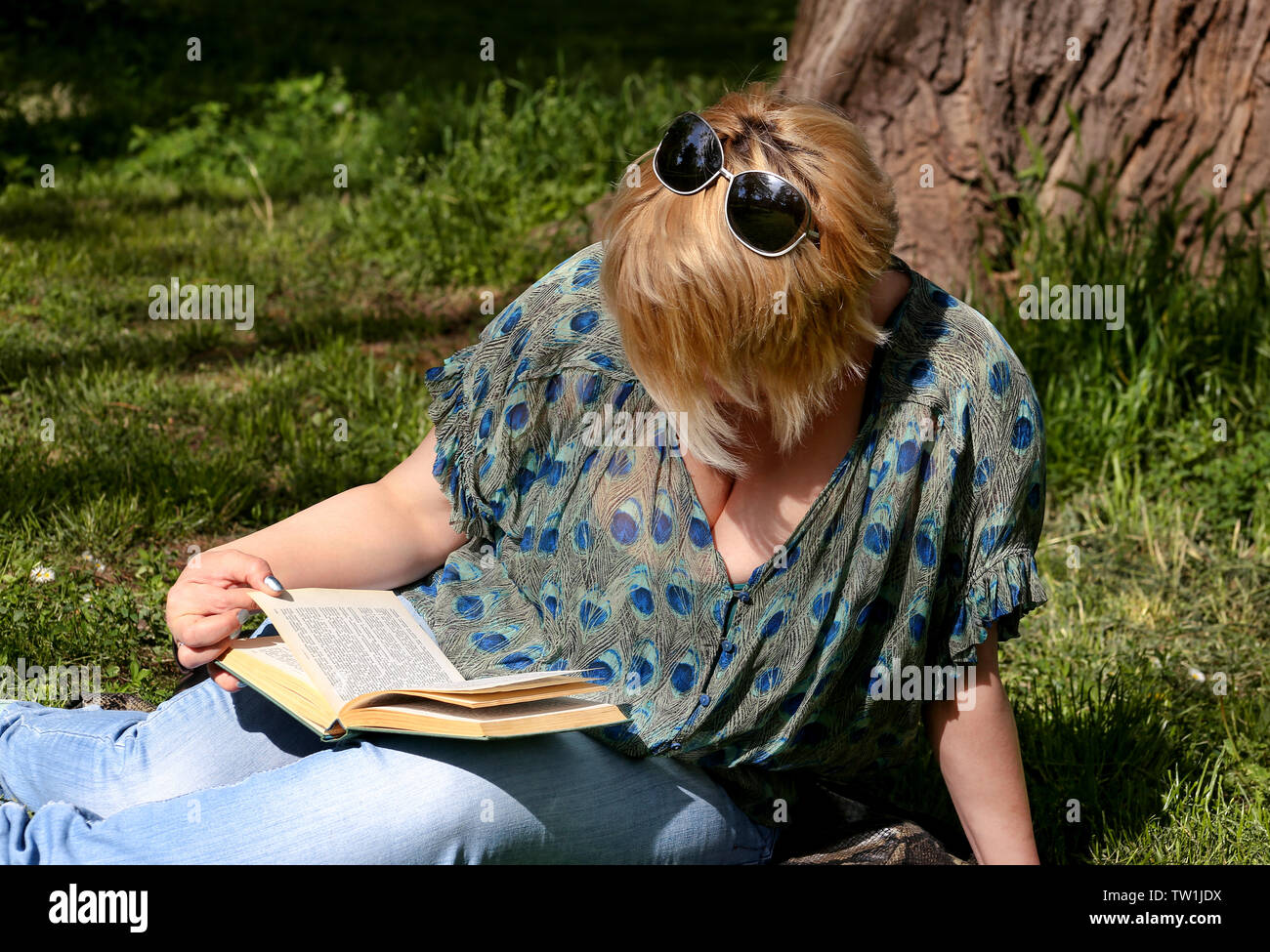 Schön mode Frau liegt auf grünem Gras und Lesen eines interessanten Buches, im Stadtpark, am Sommer, der Tag. Gut aussehender student Frau sitzt und liest. Stockfoto