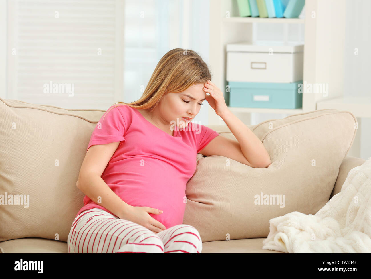 Schwangere Frau leidet unter Kopfschmerzen beim Sitzen auf dem Sofa zu Hause Stockfoto