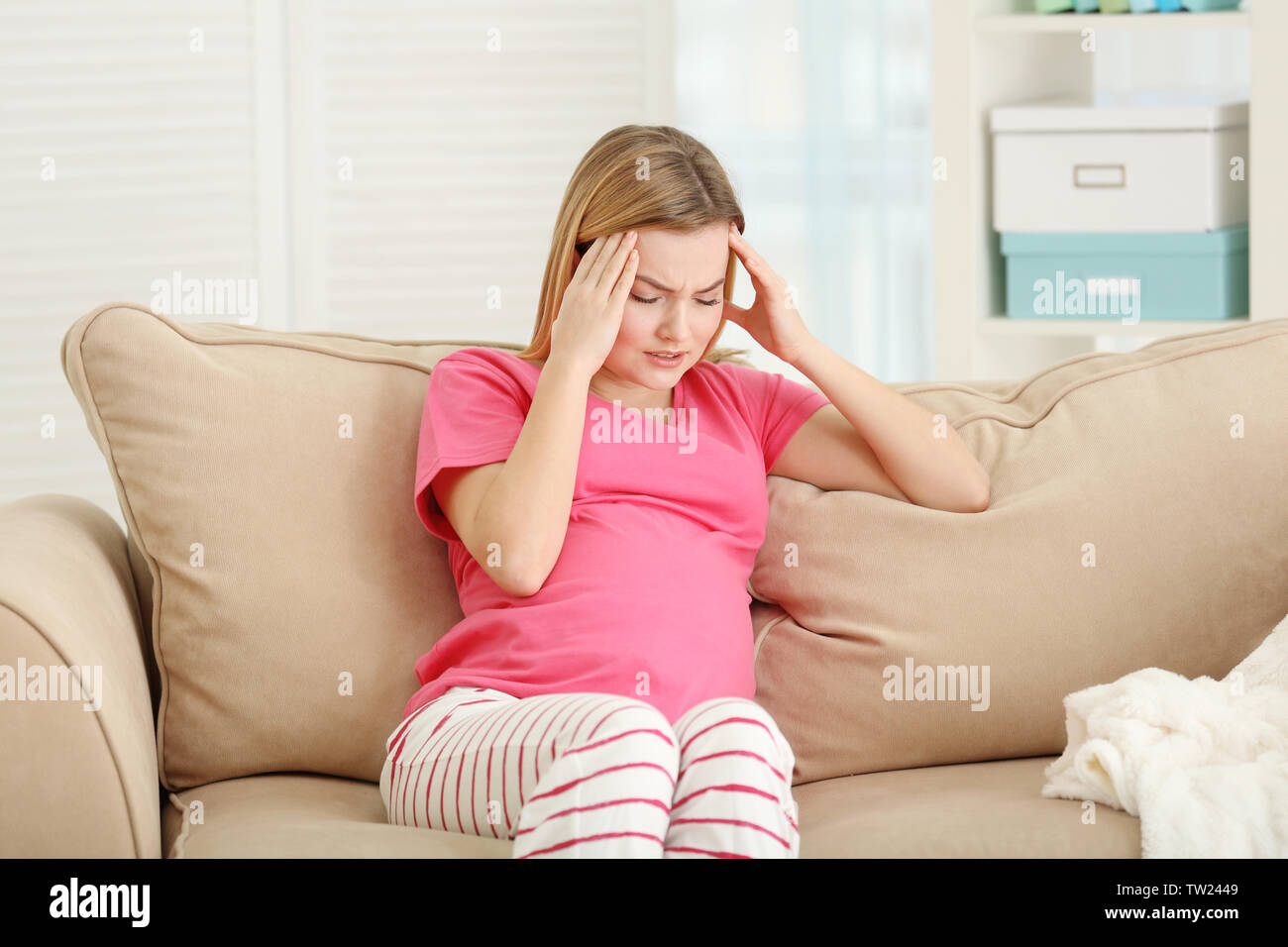 Schwangere Frau leidet unter Kopfschmerzen beim Sitzen auf dem Sofa zu Hause Stockfoto