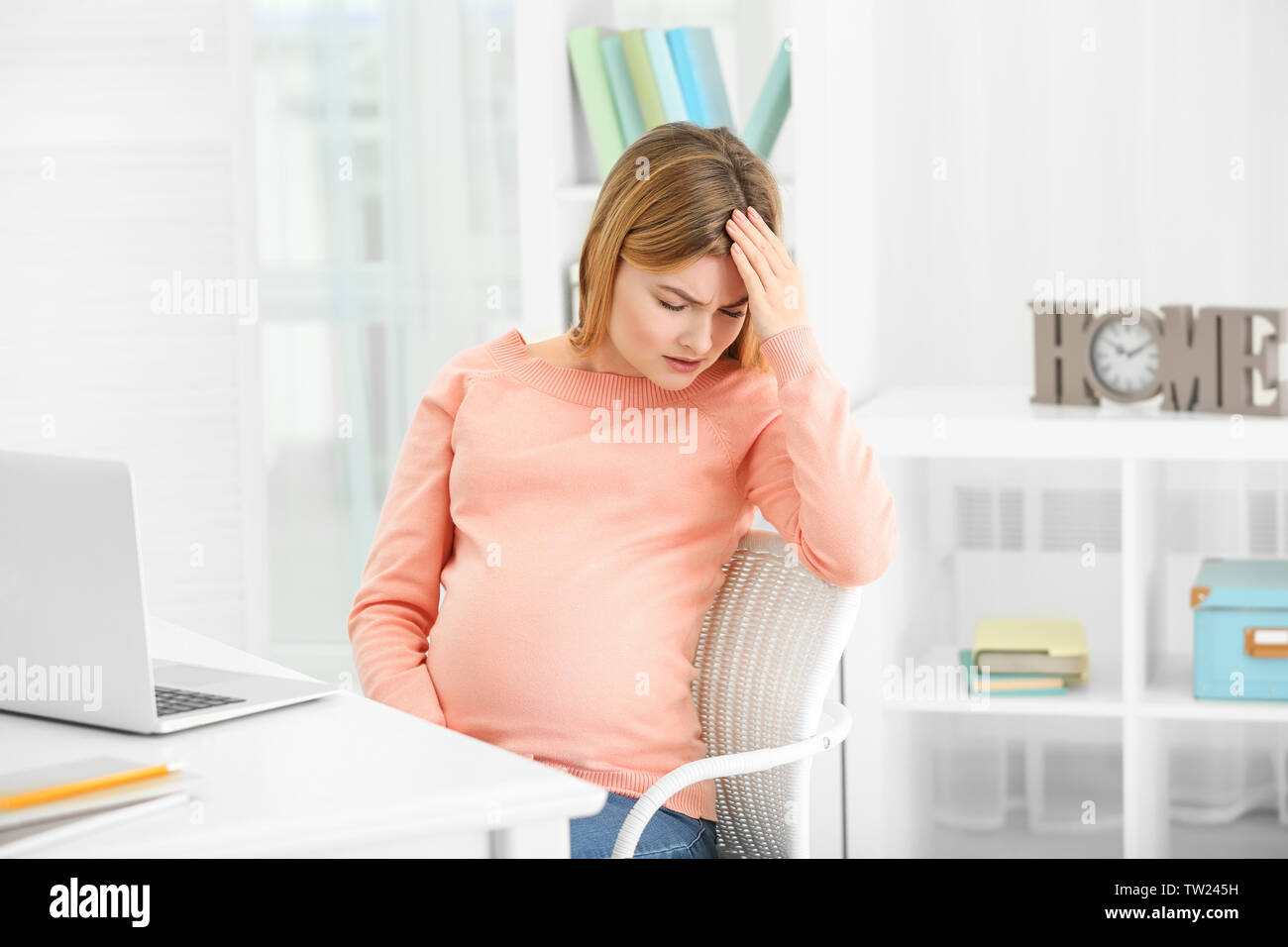 Schwangere Frau leidet unter Kopfschmerzen beim Sitzen am Arbeitsplatz im Büro Stockfoto