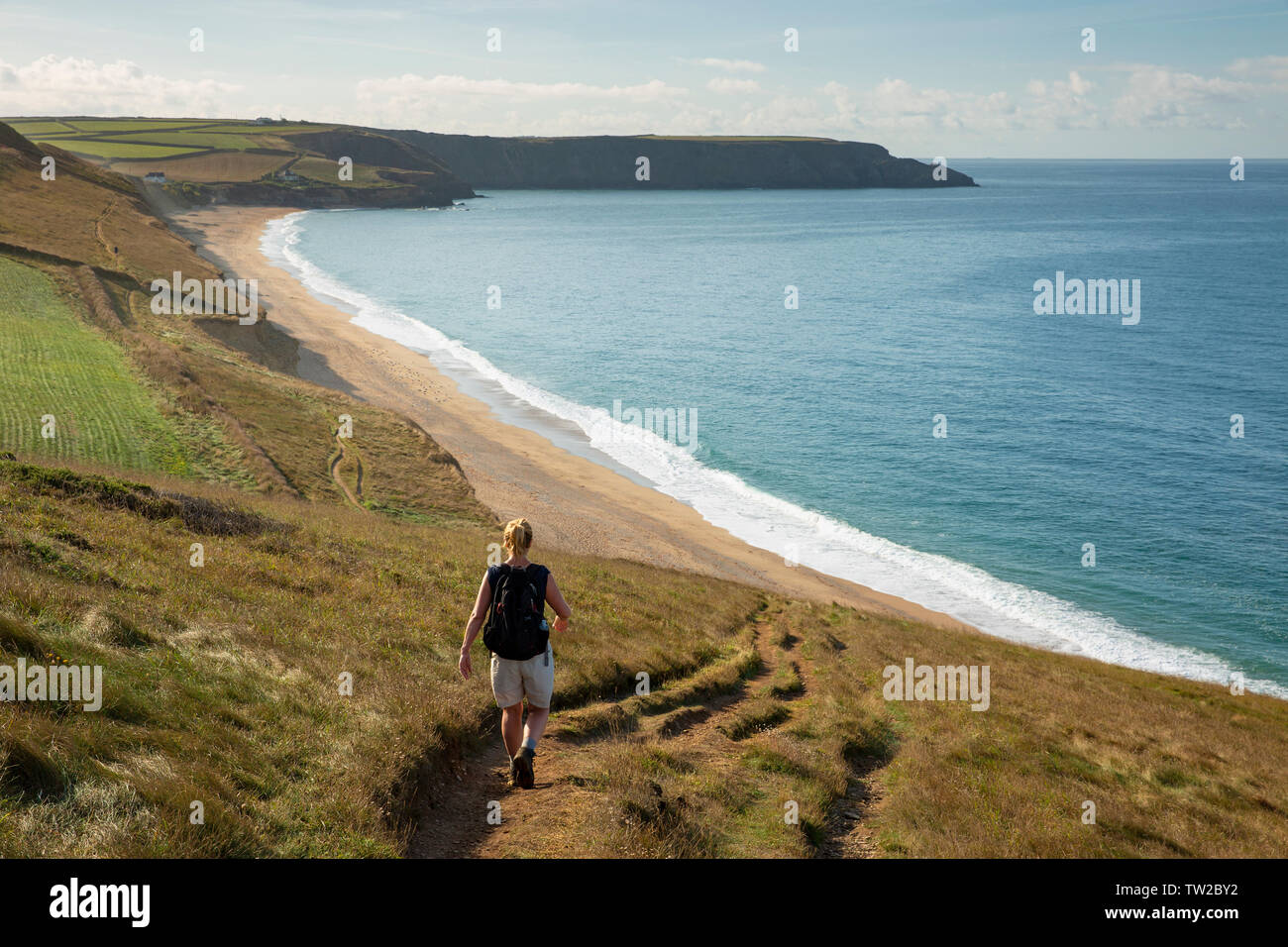 Eine Frau Spaziergänge entlang des South West Coast Path oben Porthleven Sands in Cornwall, England. Stockfoto
