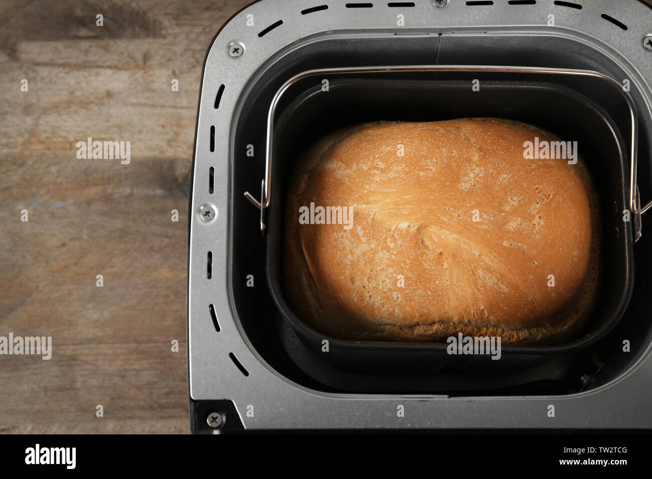 Maschine mit Laib Brot auf hölzernen Tisch Stockfoto