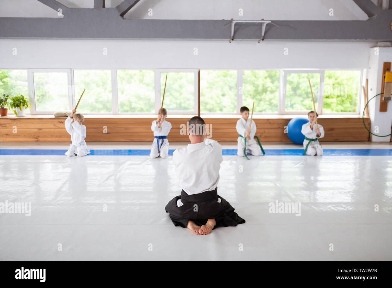 Begabte Kinder. Vier begabte Jungen und Mädchen sitzen in der Nähe der Fenster lernen aikido Bewegungen Stockfoto