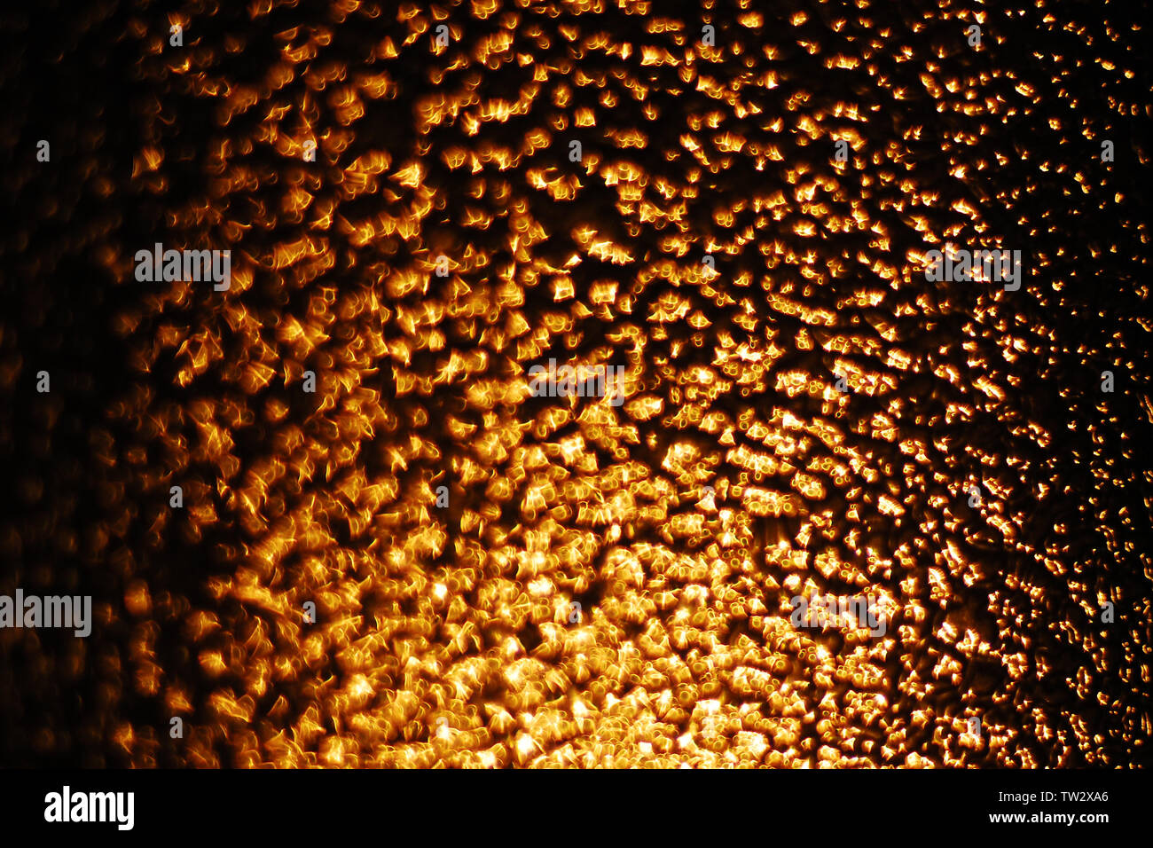 Zusammenfassung Hintergrund von Golden defokussierten Highlights auf braunem Hintergrund, Licht der untergehenden Sonne durch strukturierte Glas Stockfoto