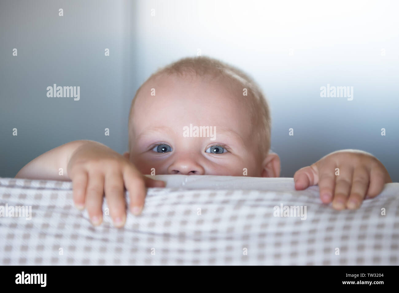 Wenig toddler Boy Spielen auf dem Bett. Cute kid lächelnd und versteckt sich unter der Abdeckung. Palyful und schelmischen Augen. Verstecken. Kinder Spaß verscherzen Stockfoto