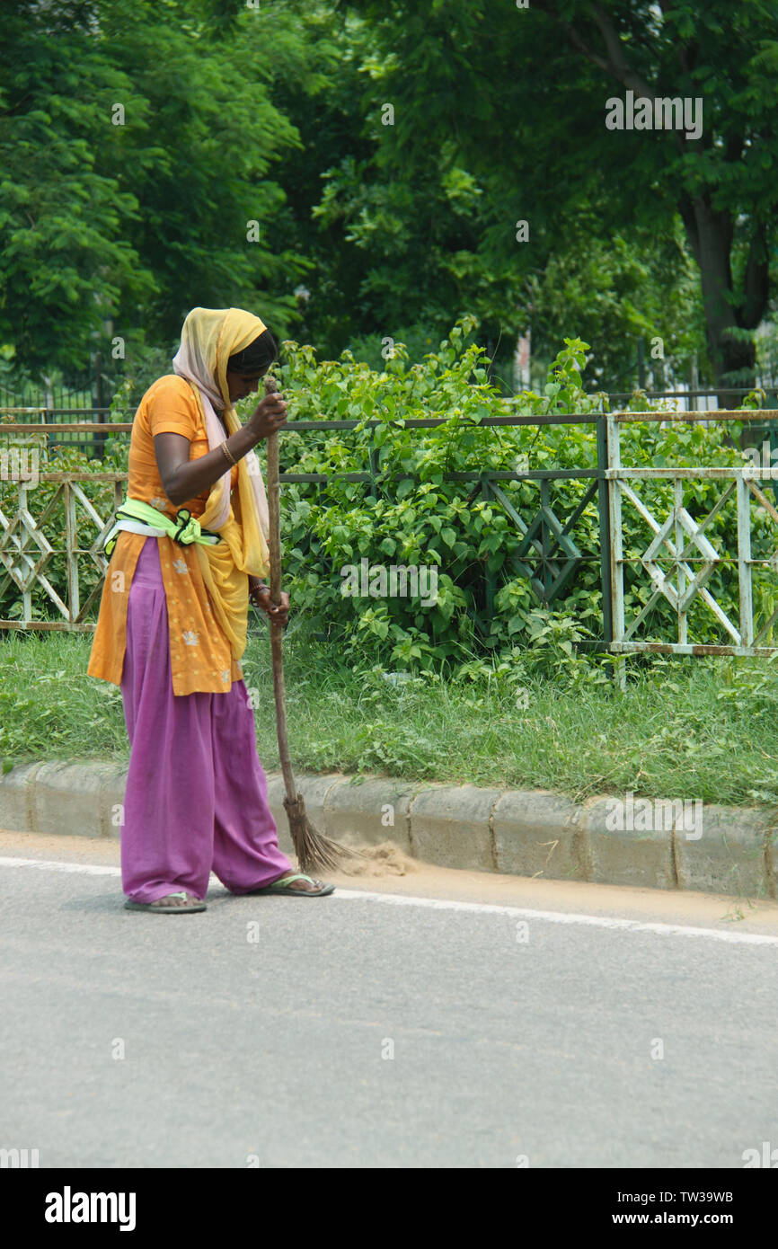 Frau, die auf der Straße fegen, Indien Stockfoto