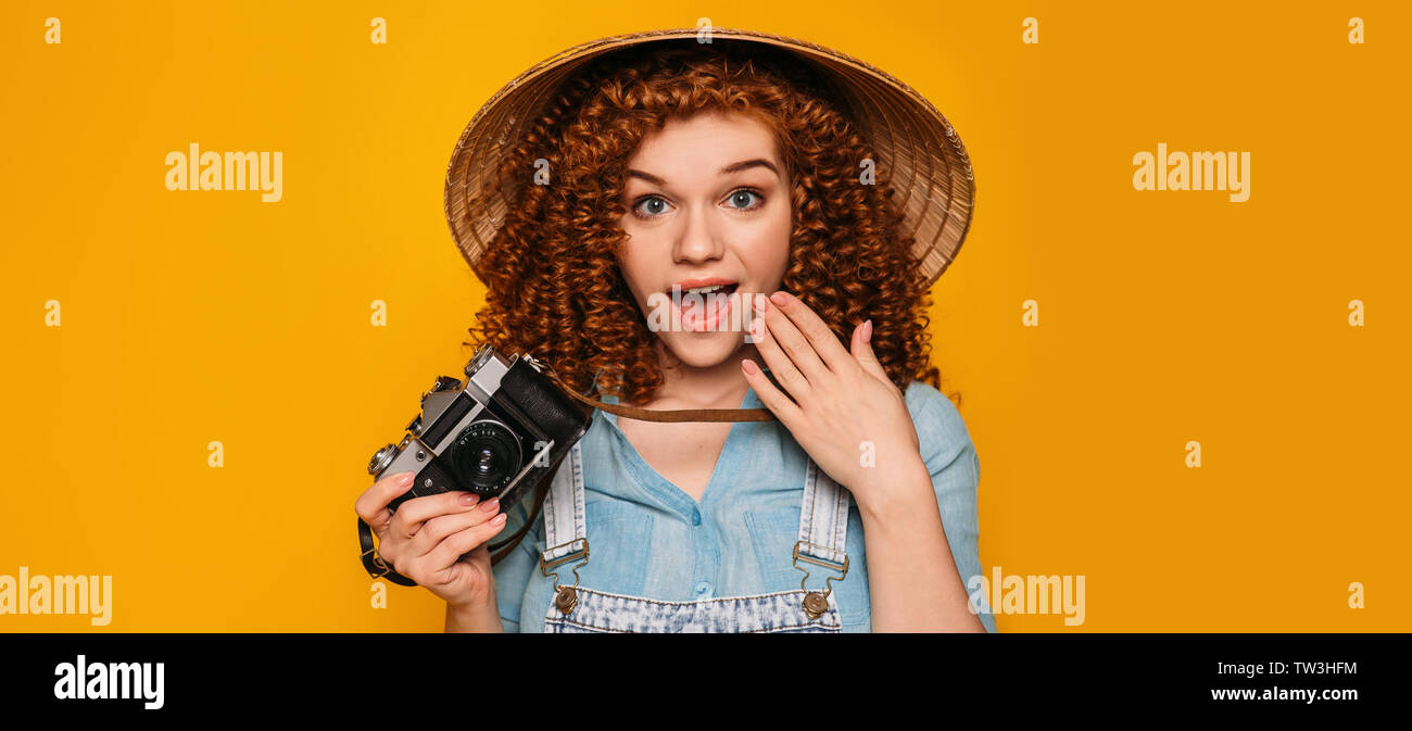 Touristische Frau in Stroh Hut mit Foto Kamera, überrascht. Reisende sagen wow auf Gelb Stockfoto