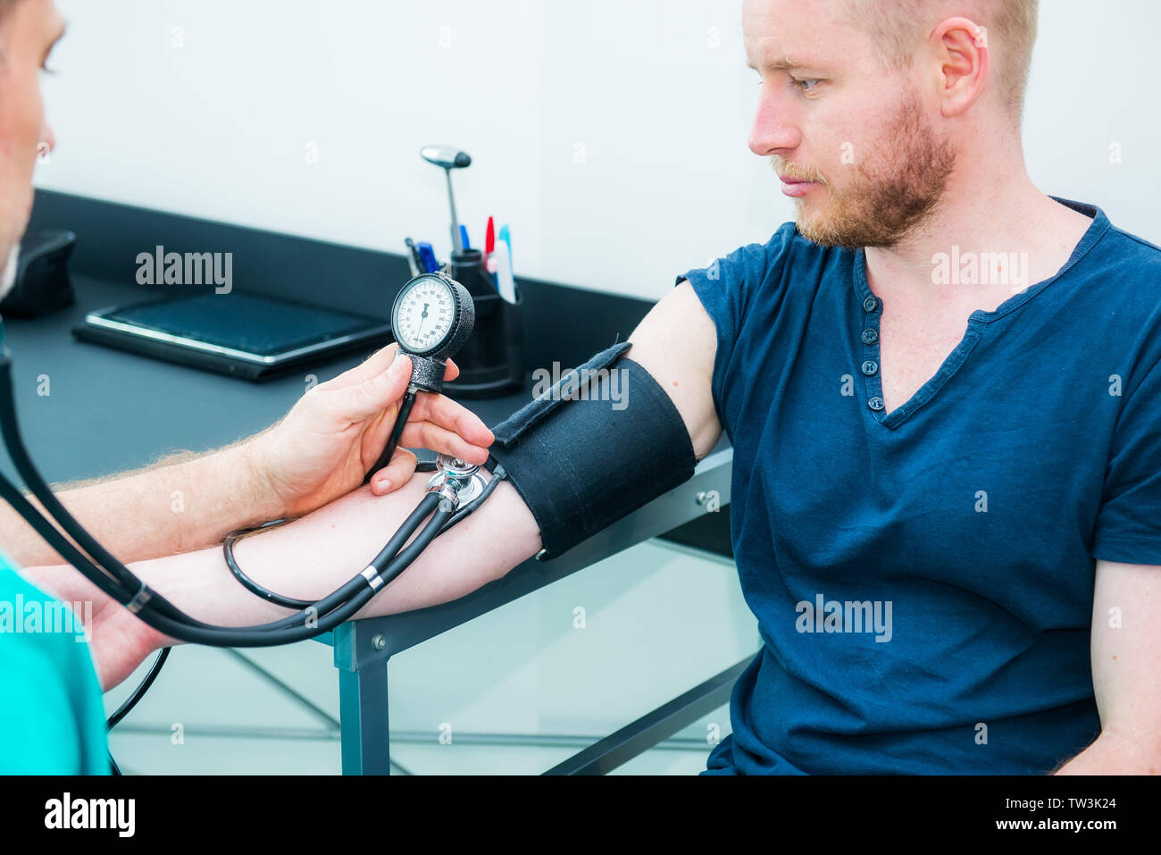 Männlicher Arzt mit Blutdruckmessgerät mit Stethoskop Kontrolle Blutdruck  zu einer jungen männlichen Patienten im Krankenhaus. Gesundheitswesen,  gesunden Lebensstil und Stockfotografie - Alamy