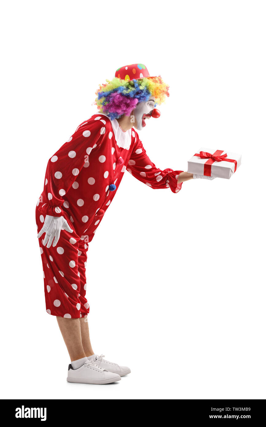 Volle Länge Profil Schuß eines Clowns ein Geschenk Box auf weißem Hintergrund Stockfoto
