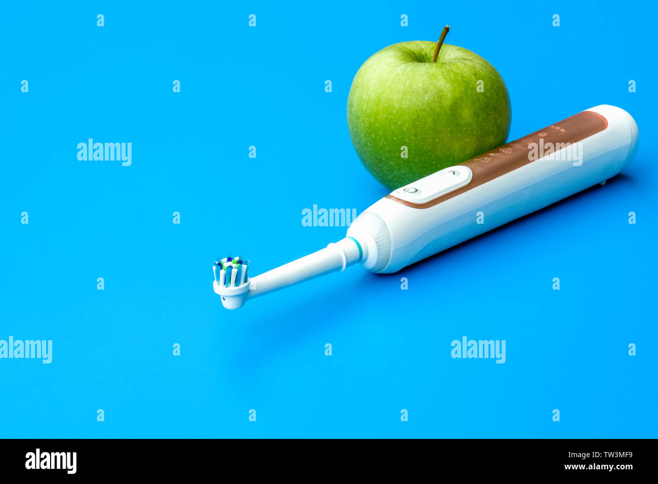 Zahnarzt Konzept grüner Apfel und elektrische Zahnbürste auf blauem Hintergrund-Bild Stockfoto