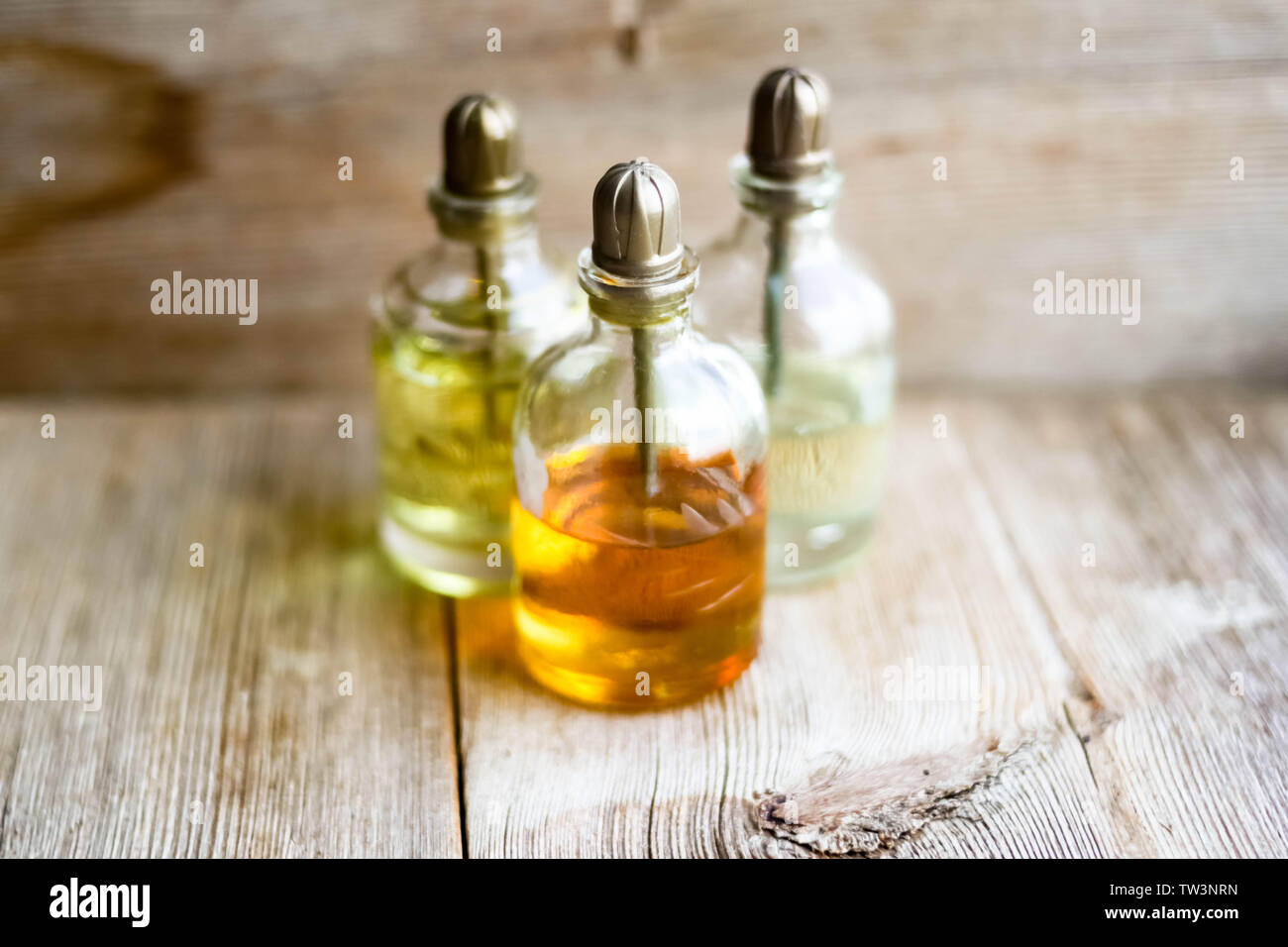 Parfum essence Aroma öl Glas Flaschen in der Nähe von alten hölzernen Hintergrund. Aromatherapie, Spa, Wellness, Entspannung, Massage und Kräutermedizin Konzept. Co Stockfoto