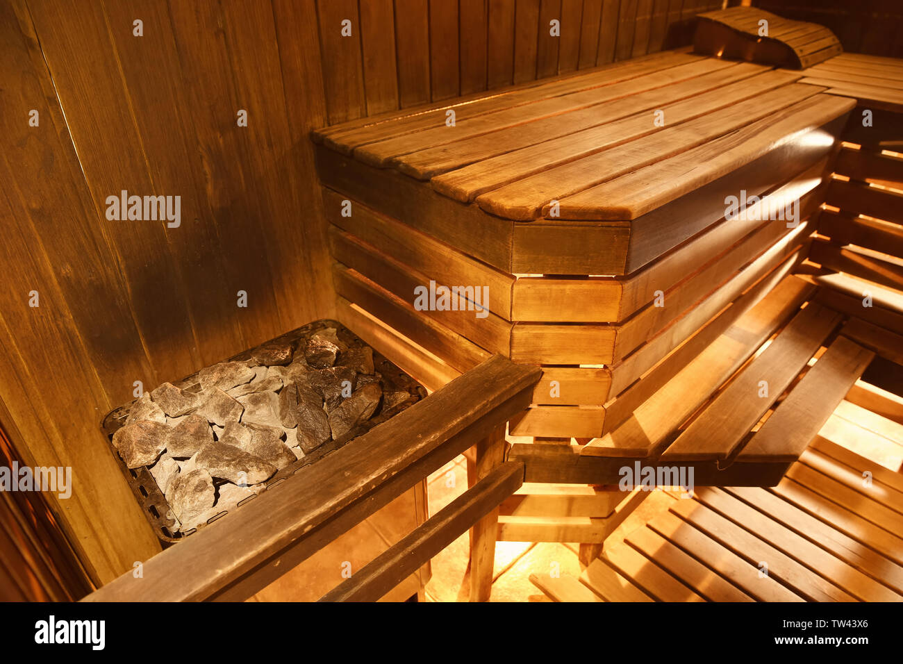 Kessel mit heißen Steinen und Holzbank in der Sauna Stockfoto