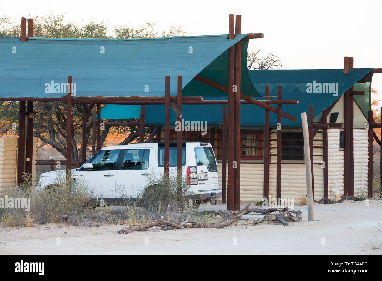 Einfache Unterkunft Chalets oder Hütten von Groot Kolk Wildnis Camp, Kgalagadi Transfrontier Park in Südafrika mit einem weißen 4x4 off road Auto geparkt Stockfoto