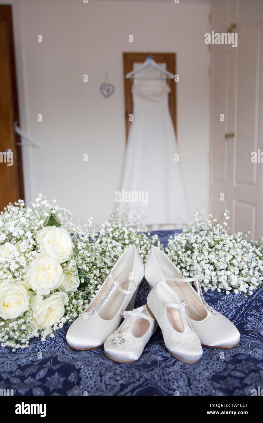 Bräute Hochzeit Kleid Auflegen mit Schuhen und Blumen an der Vorderseite des Foto, warten Alle getragen zu werden von der Braut an ihrem Hochzeitstag. Stockfoto