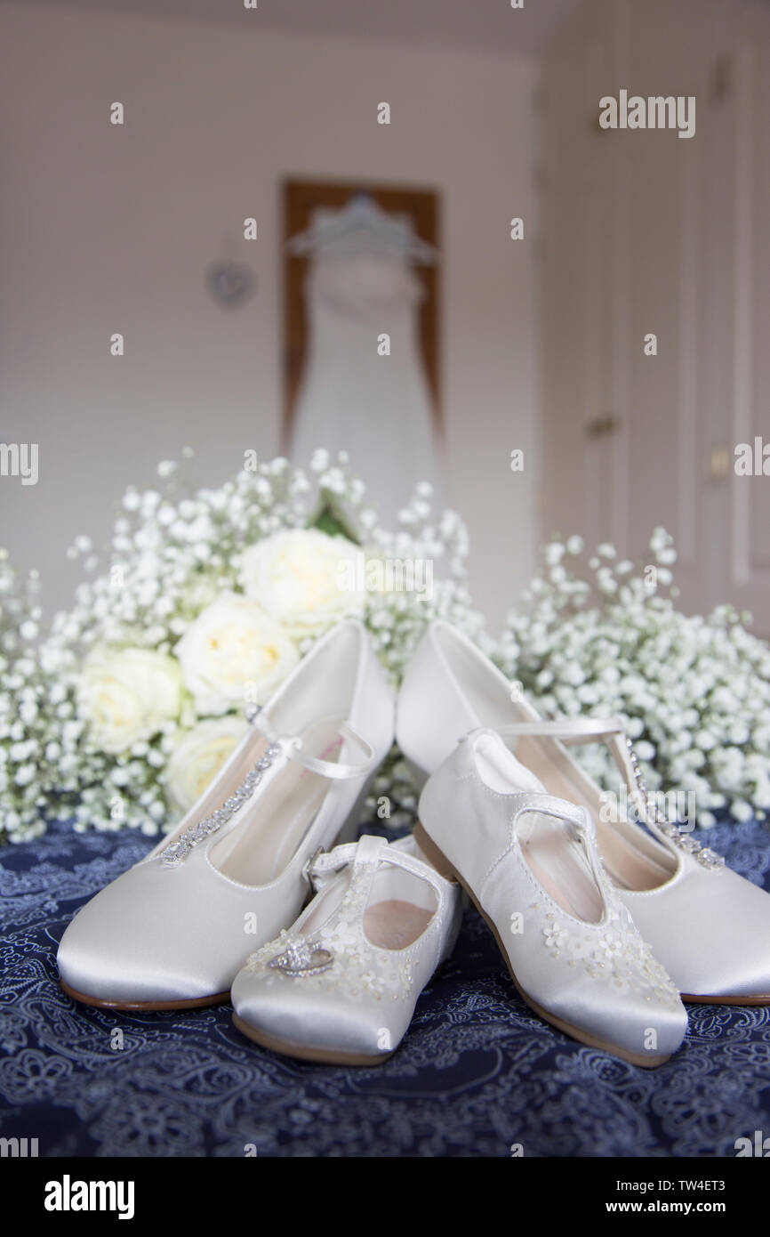 Bräute Hochzeit Kleid Auflegen mit Schuhen und Blumen an der Vorderseite des Foto, warten Alle getragen zu werden von der Braut an ihrem Hochzeitstag. Stockfoto