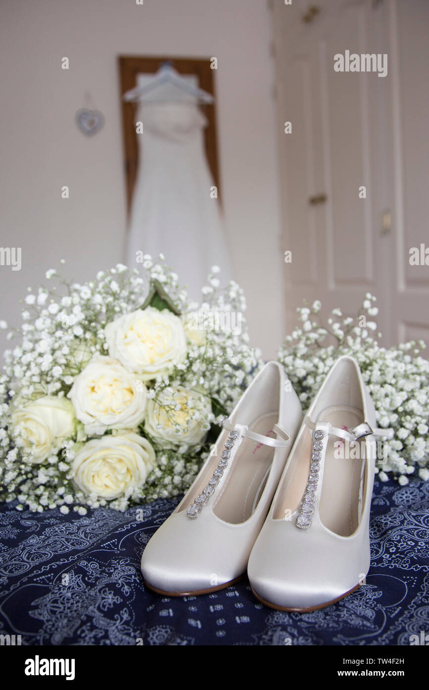 Bräute Hochzeit Kleid Auflegen mit Schuhen und Blumen an der Vorderseite des Foto, warten Alle getragen zu werden von der Braut an ihrem Hochzeitstag. Stockfoto
