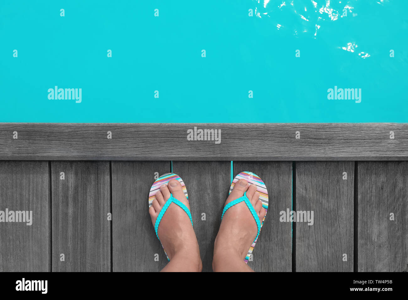 Füße der Frau in flip-flops stehen auf hölzernen Ponton an Sea Resort. Sommer Urlaub Konzept Stockfoto