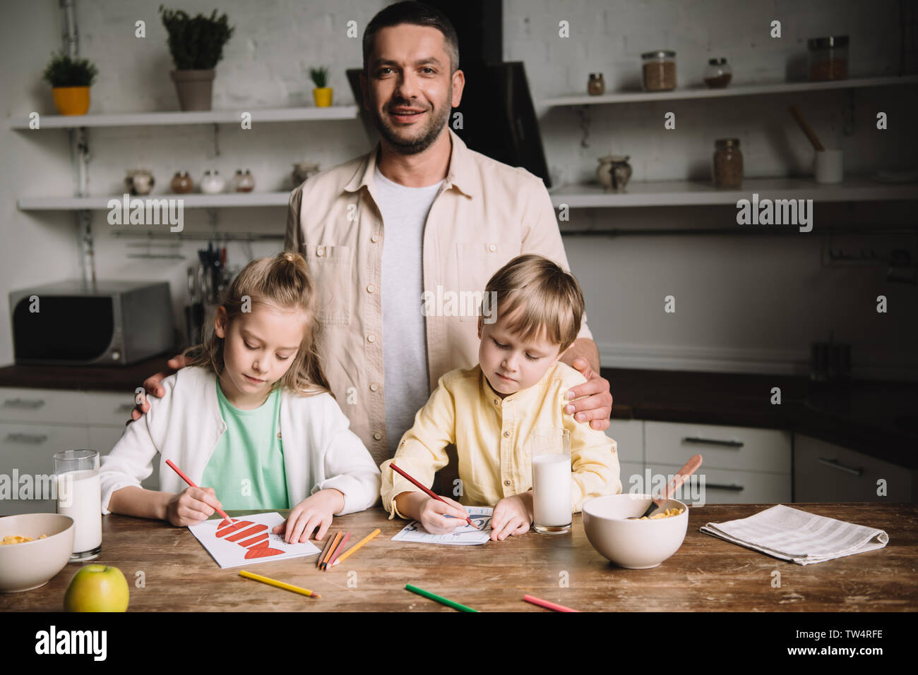 Gerne Vater in der Nähe von adorable Kinder Zeichnung Vatertag Grußkarten am Küchentisch Stockfoto