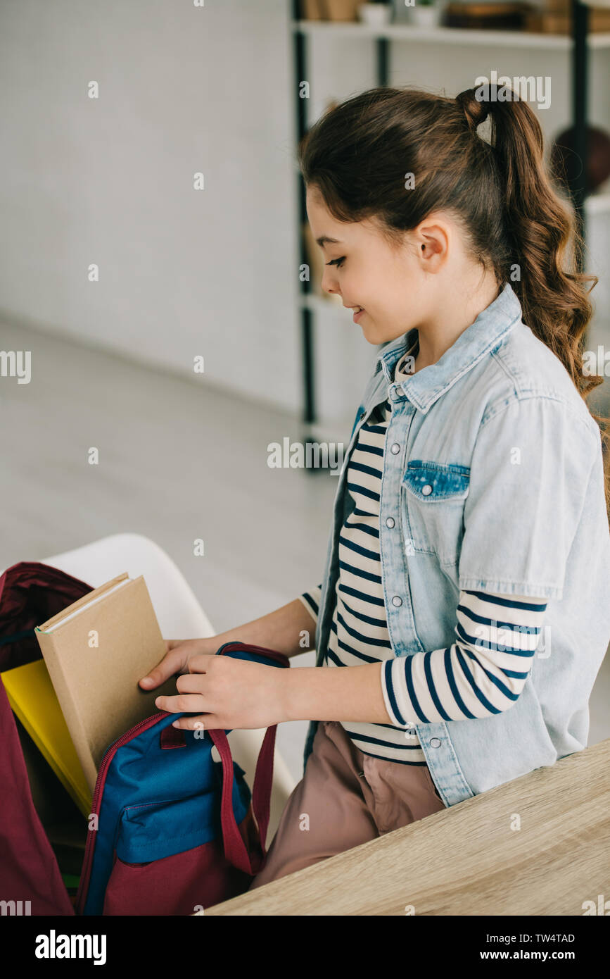 Adorable Kind die Bücher in Back Pack beim Stehen in der Nähe des Schreibtisch zu Hause Stockfoto