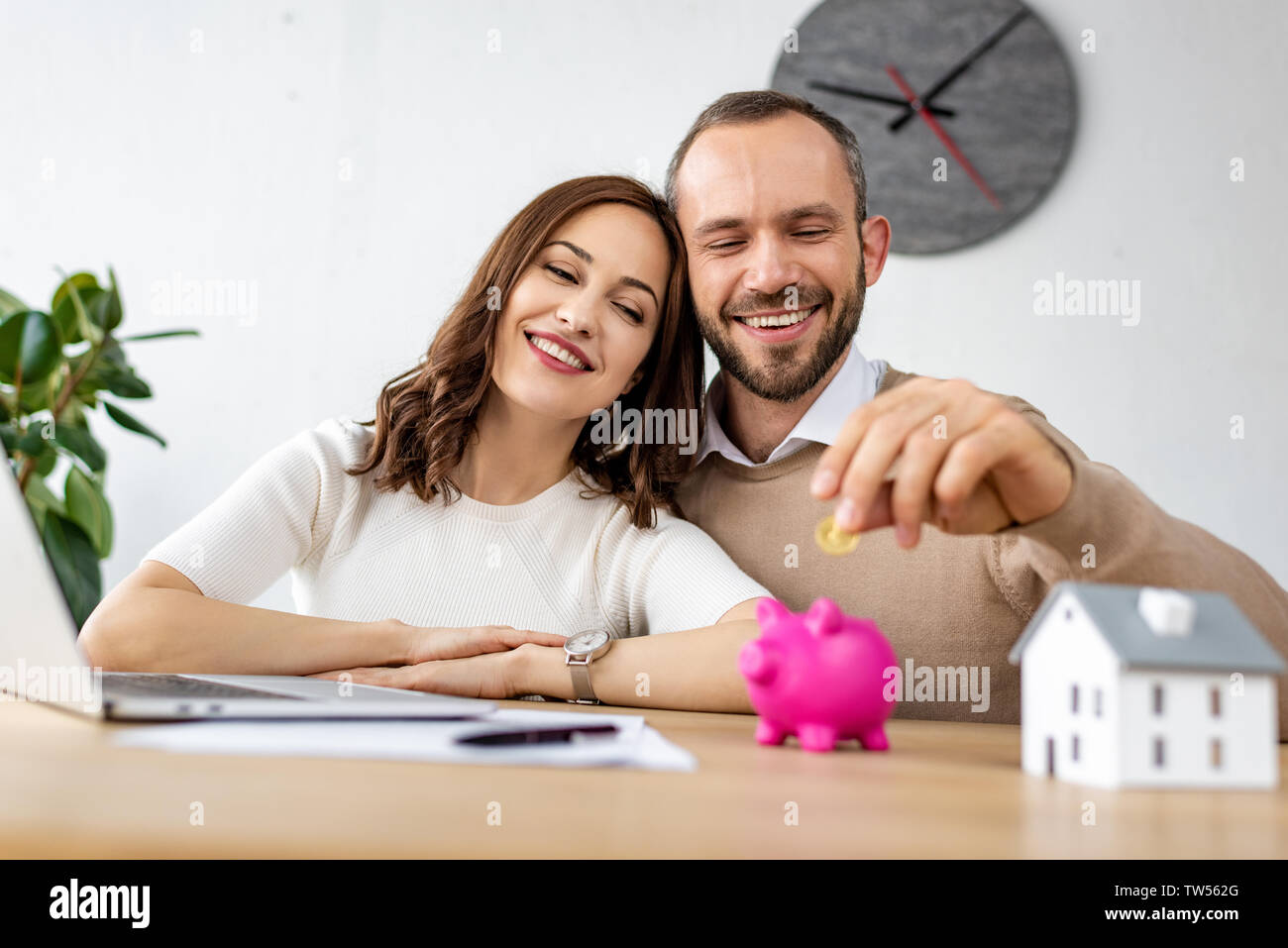 Selektiver Fokus der glücklichen Mann die goldene Münze in rosa Sparschwein in der Nähe von attraktiven Frau Stockfoto