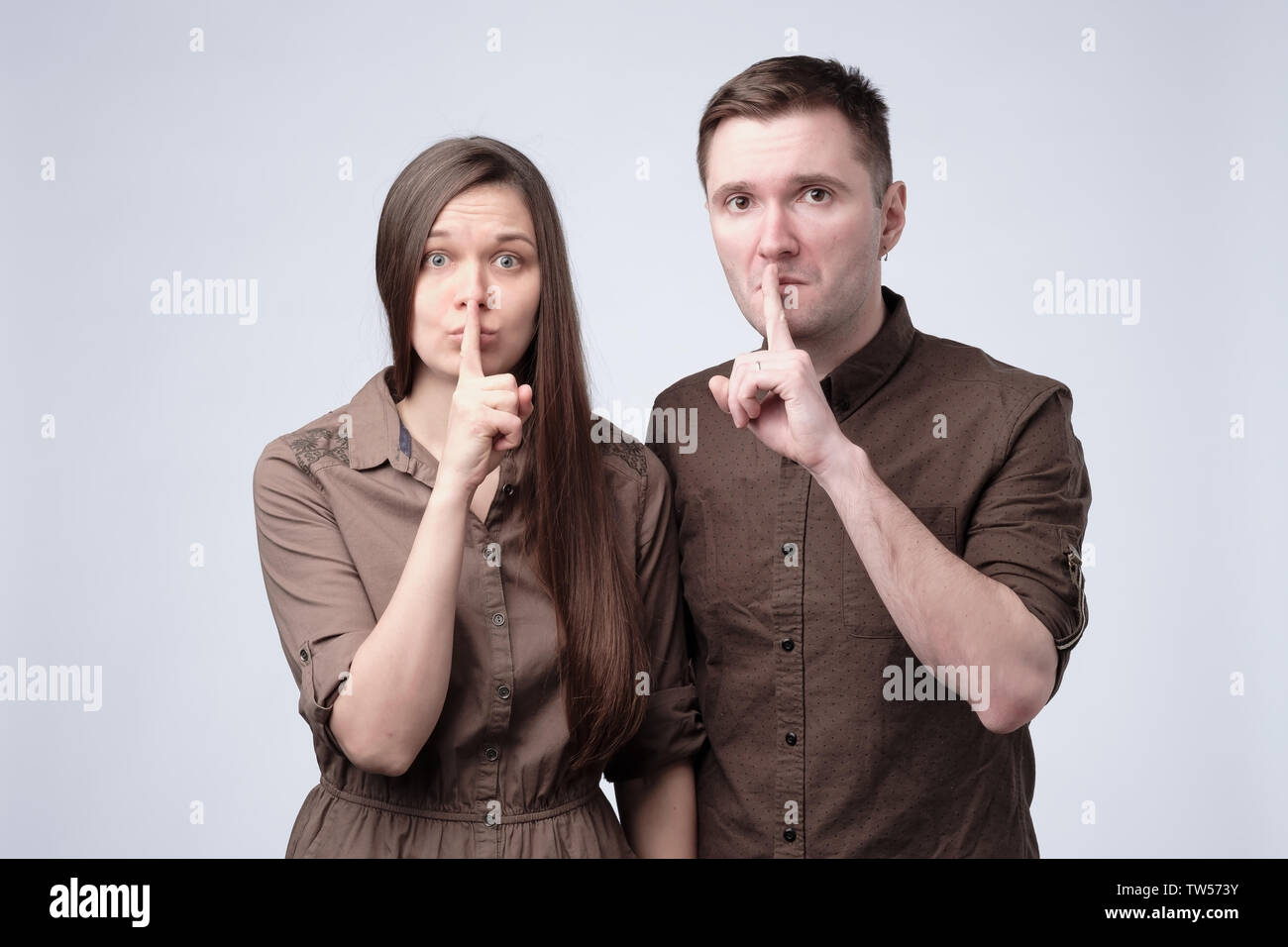 Junger Mann und Frau ihre Finger halten an Lippen, still zu sein Stockfoto
