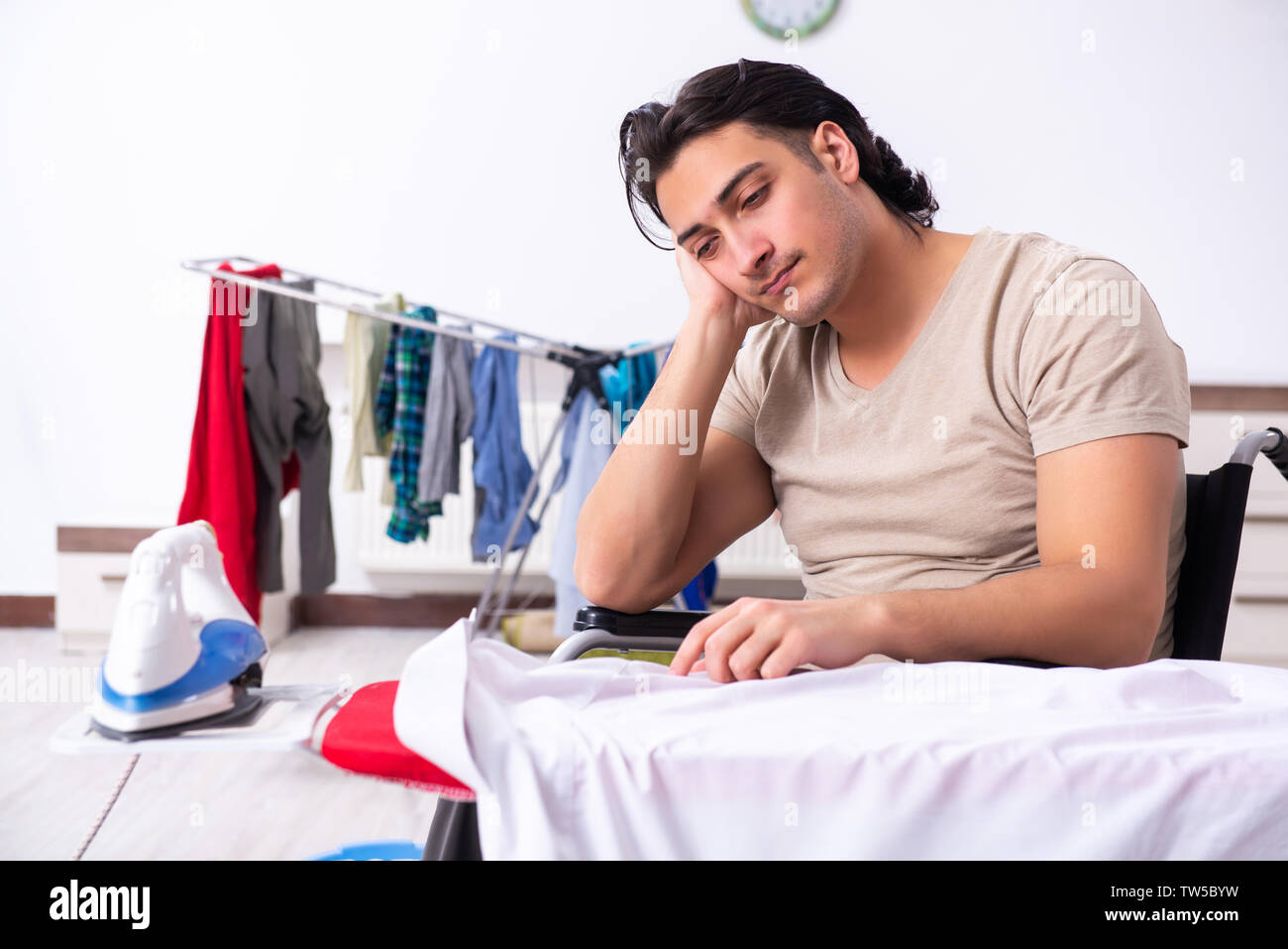 Junger Mann Im Rollstuhl Bugeleisen Brett Zu Hause Stockfoto