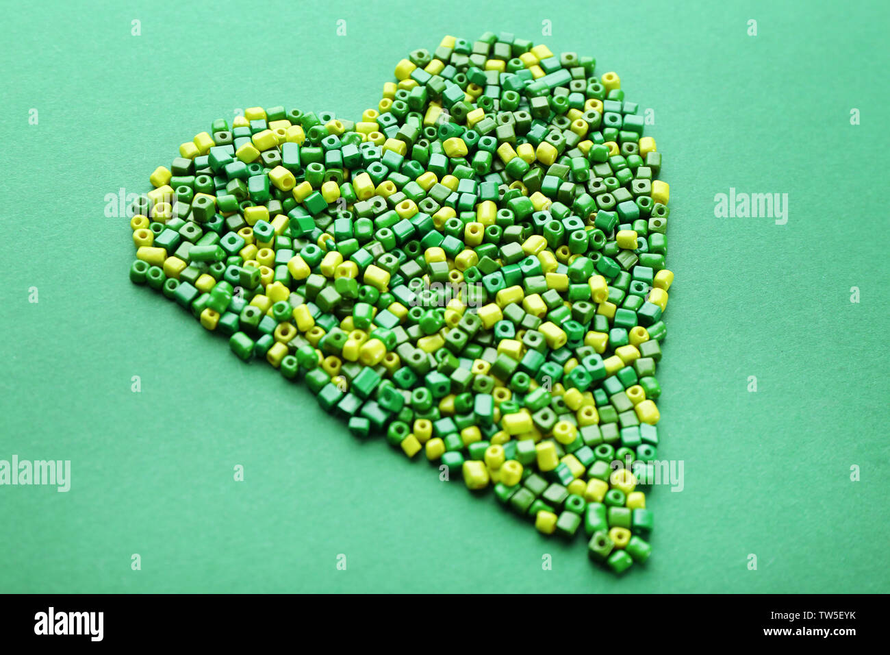 Perlen in Herzform auf grünem Hintergrund Stockfoto