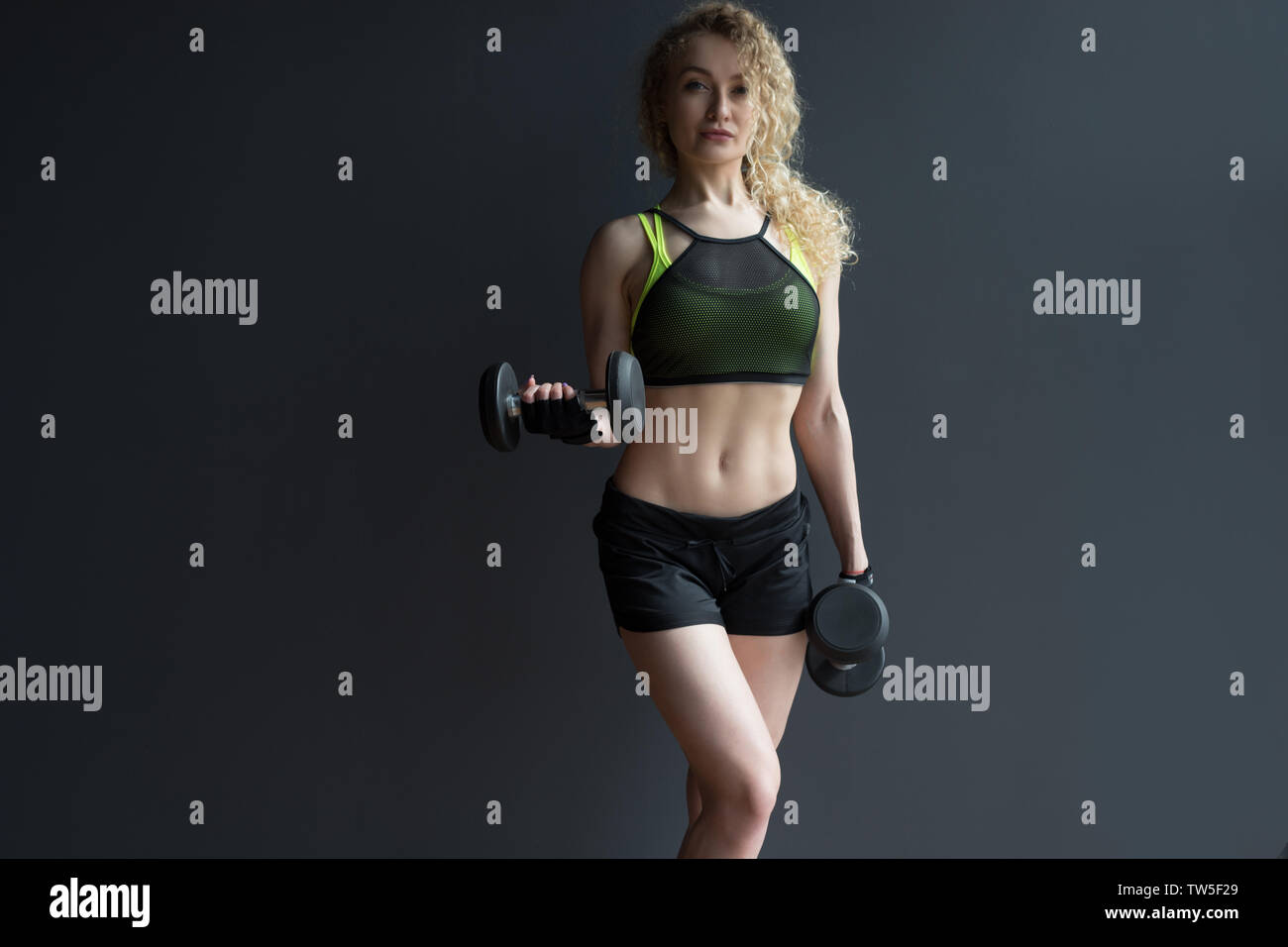 Sportliche Frau, die Übungen mit Hanteln im Fitnessstudio. Stockfoto