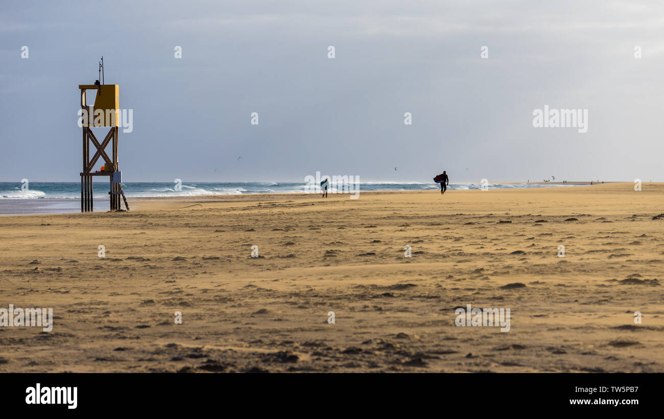 Silhouette von Kitesurfer zu Fuß am Strand nach einem harten Tag. Windigen Strand mit Bademeister Turm am Nachmittag Stockfoto