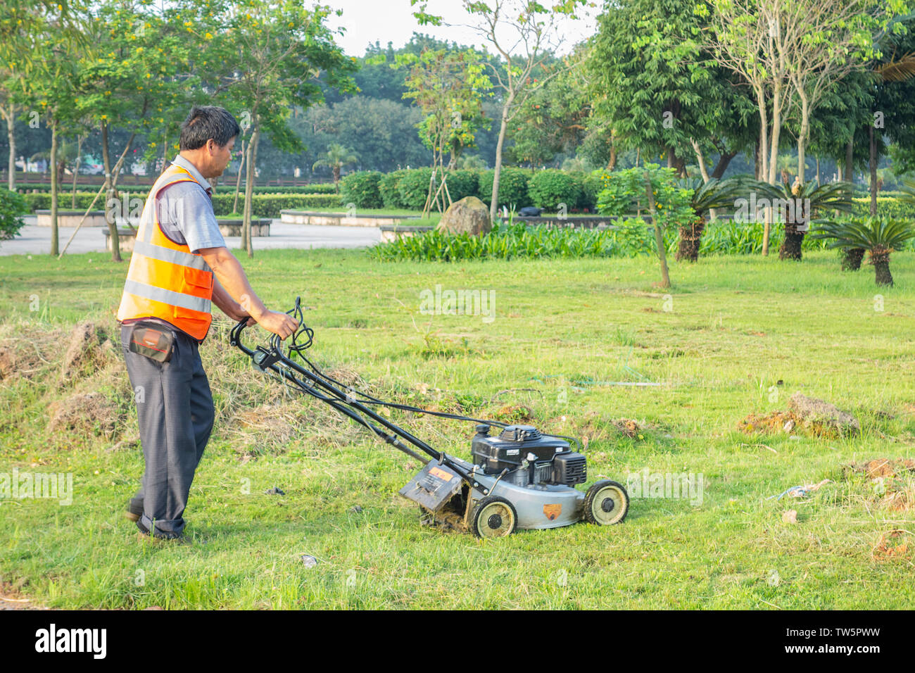 Die Ökologisierung der Arbeitnehmer wird mit einem weeder Pflege des Rasens zu nehmen. Stockfoto