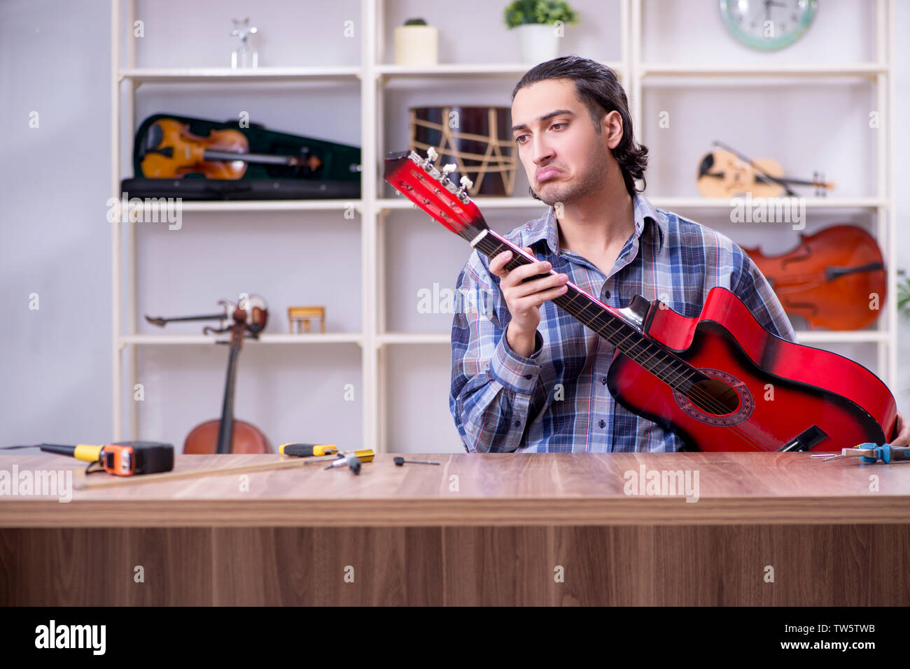 Junge schöne Handwerker Reparatur Gitarre Stockfoto