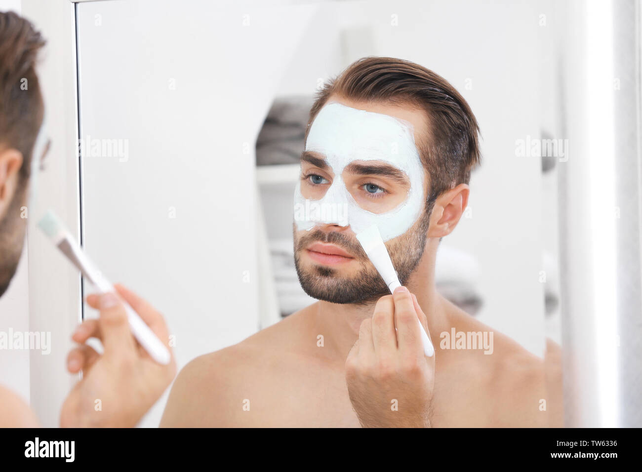 Jungen gutaussehenden Mann Auftragen kosmetischer Maske auf Gesicht in Bad Stockfoto