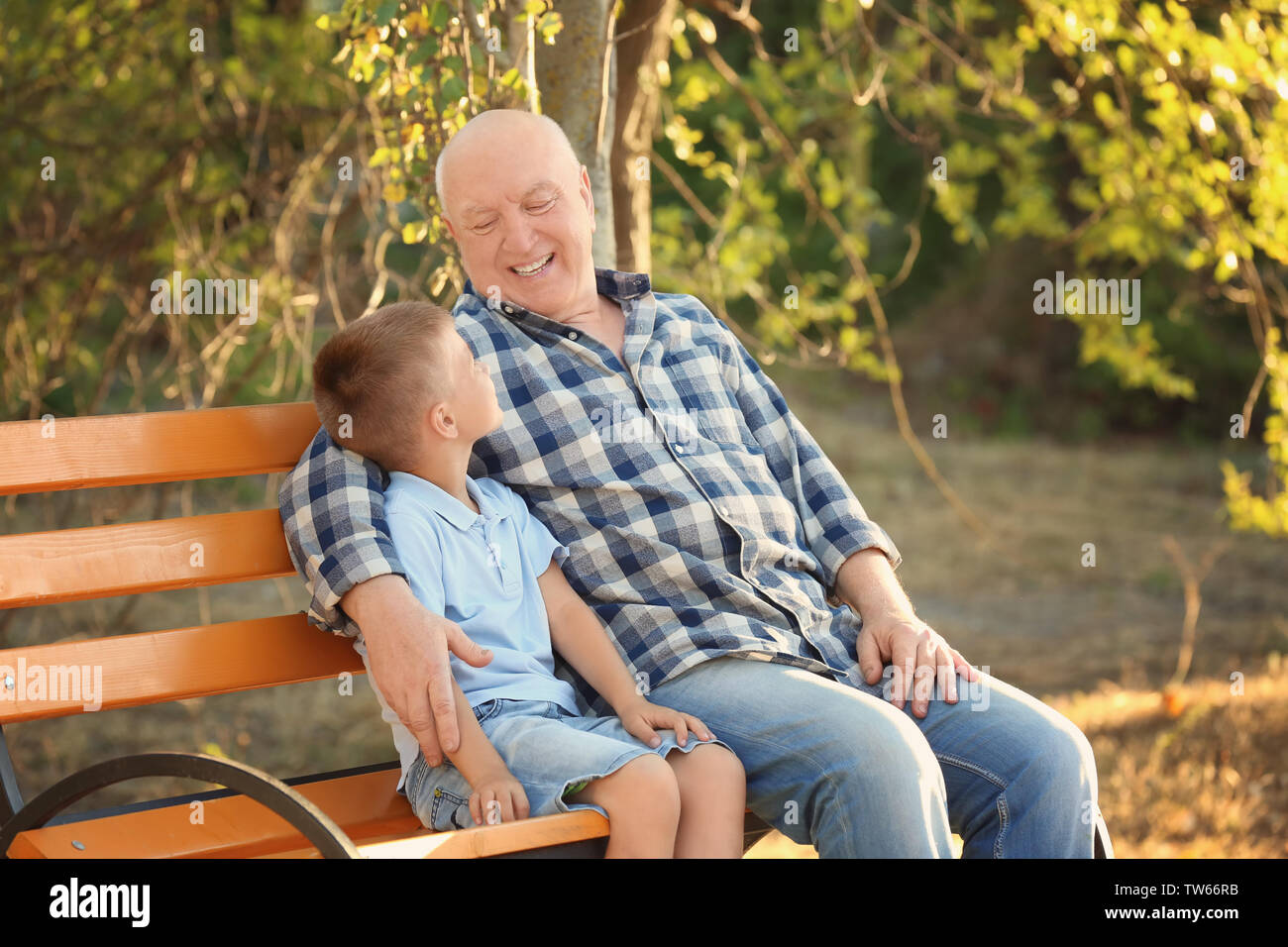 Gerne älterer Mann mit Enkel sitzt auf der Bank im Park Stockfoto