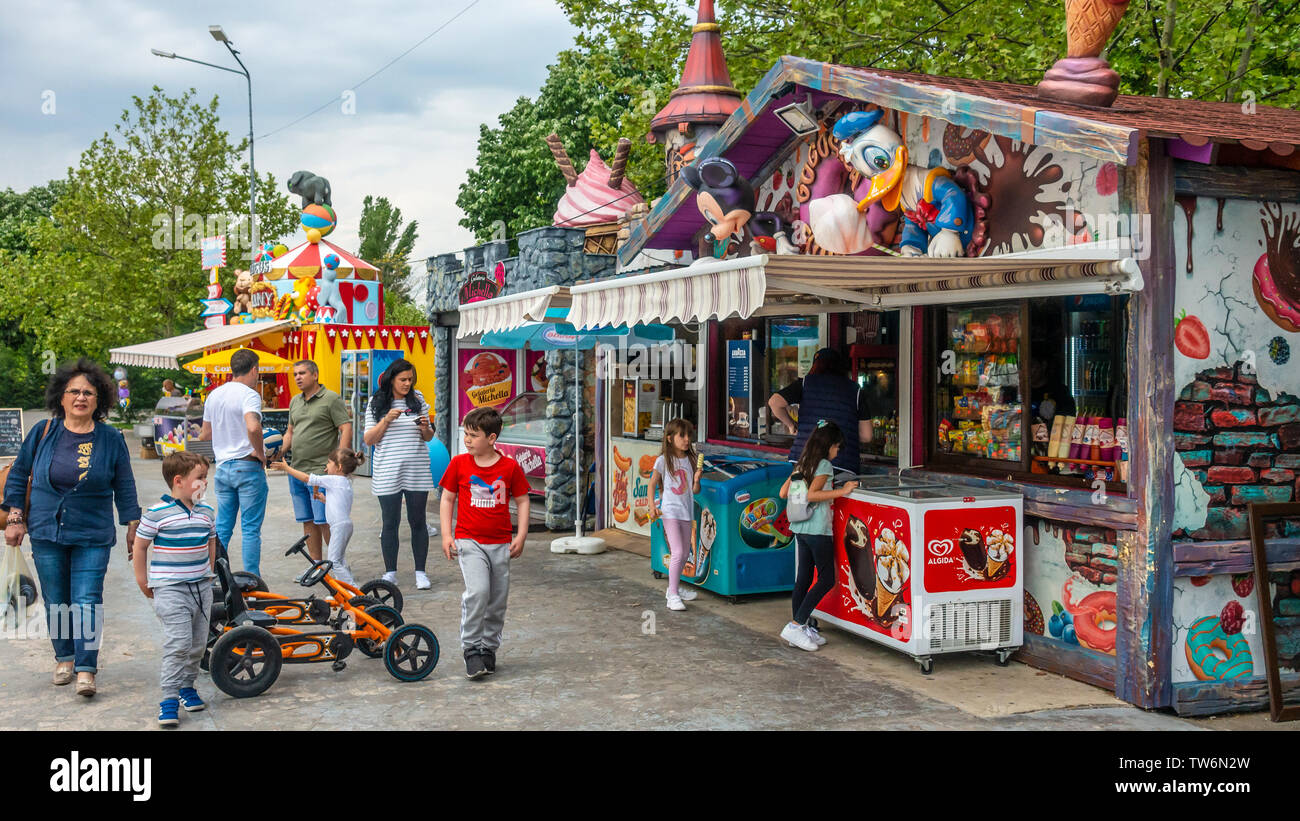 Erwachsene und Kinder in der Snackbar stall Bereich Parcul Lumea Copiilor, die "Children's World Park, im Zentrum von Bukarest, Rumänien. Stockfoto