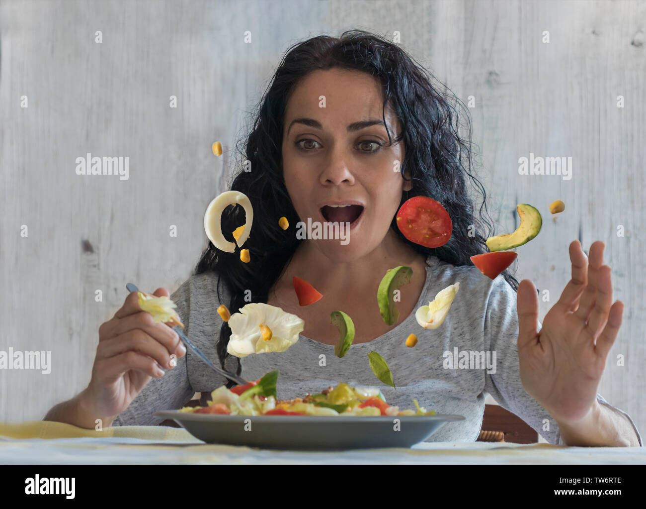 Erstaunt, brünette Frau beobachten fliegende Gemüse in Ihrem Salat. Fantasy Fotografie Stockfoto