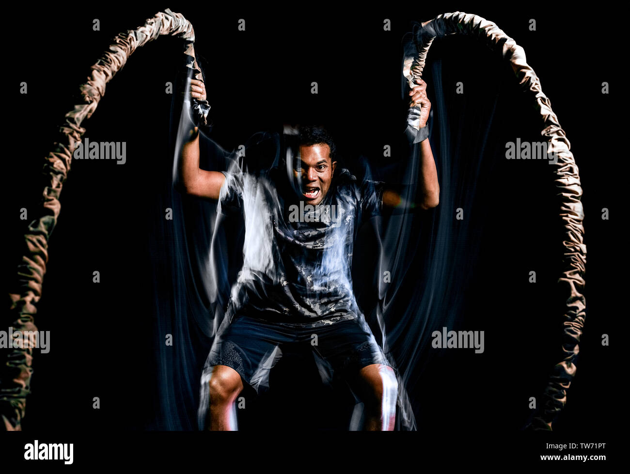 Eine afro-amerikanische Mann Training Boot Camp fitness Seile Übungen auf schwarzen Hintergrund mit Licht malen Geschwindigkeit Effekt isoliert Stockfoto