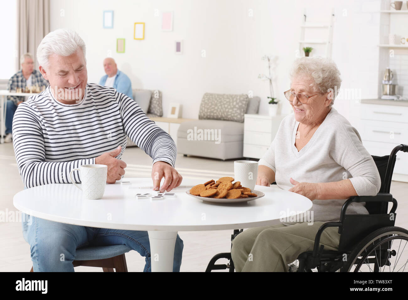 Ältere Frau Domino spielen mit ihrer Freundin beim Frühstück in der Pflege zu Hause in Stockfoto