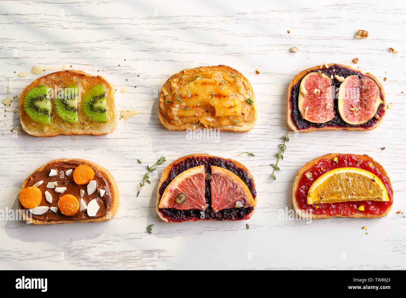 Scheiben Brot mit verschiedenen Toppings auf hellen Hintergrund Stockfoto