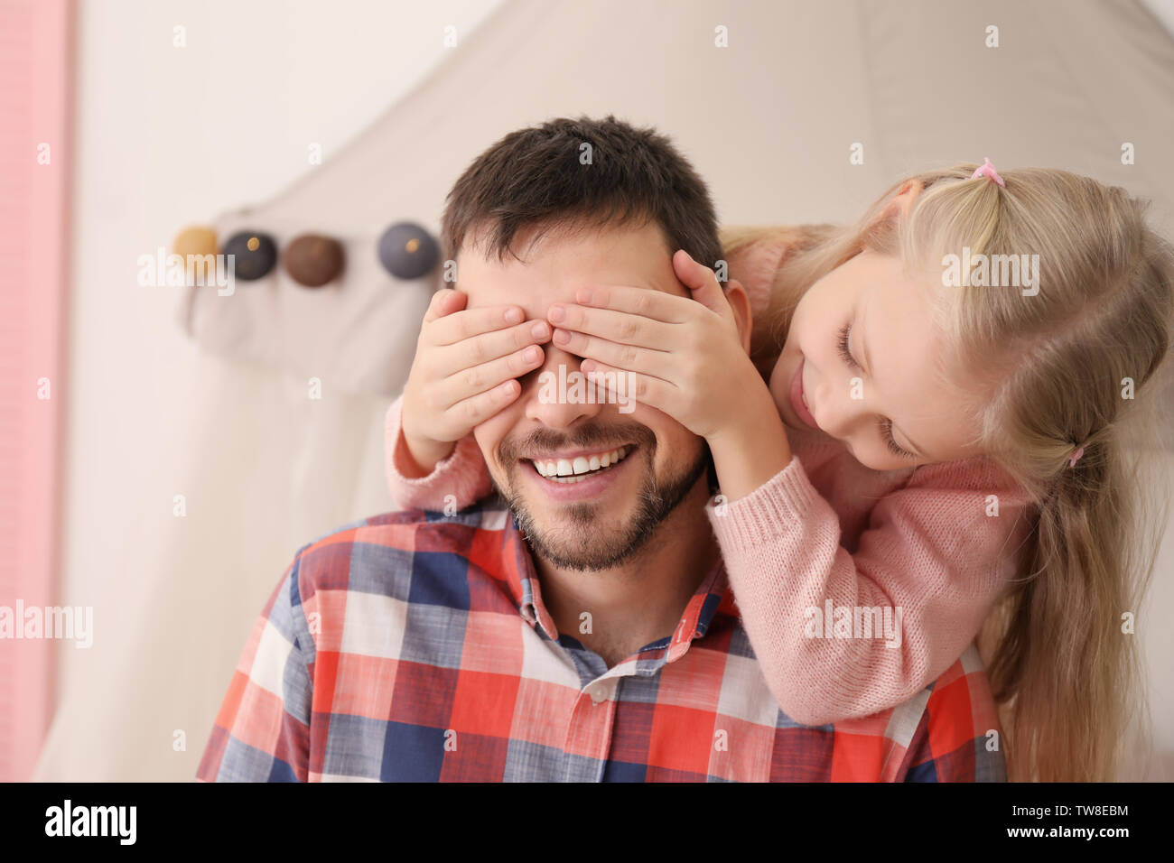 Süße Mädchen die Augen ihres Vaters mit Händen Stockfoto