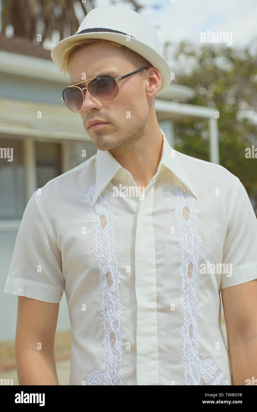 Ein hübscher, blonder Haarkater mit einem weißen Vintage-Hemd aus dem Jahr 1970s, der sich im Freien posiert. Ein männliches Outdoor-Fashion-Portrait. Stockfoto